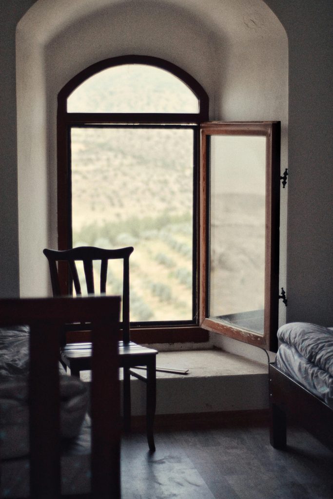 Una silla solitaria y una ventana abierta con luz, representando el proceso de duelo y la búsqueda de nuevas oportunidades tras una separación de pareja.